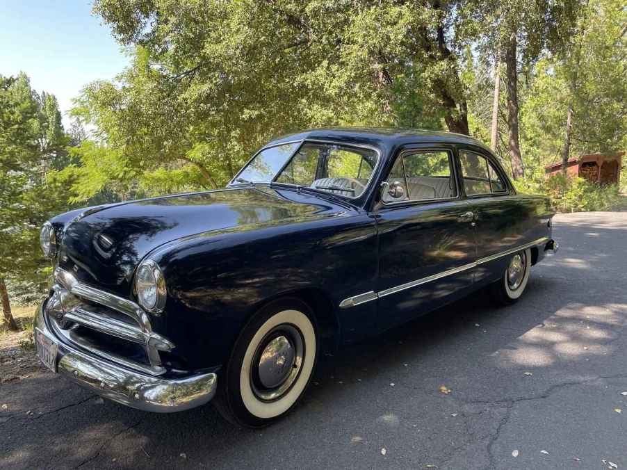 A black 1949 Ford car parked in left front angle view