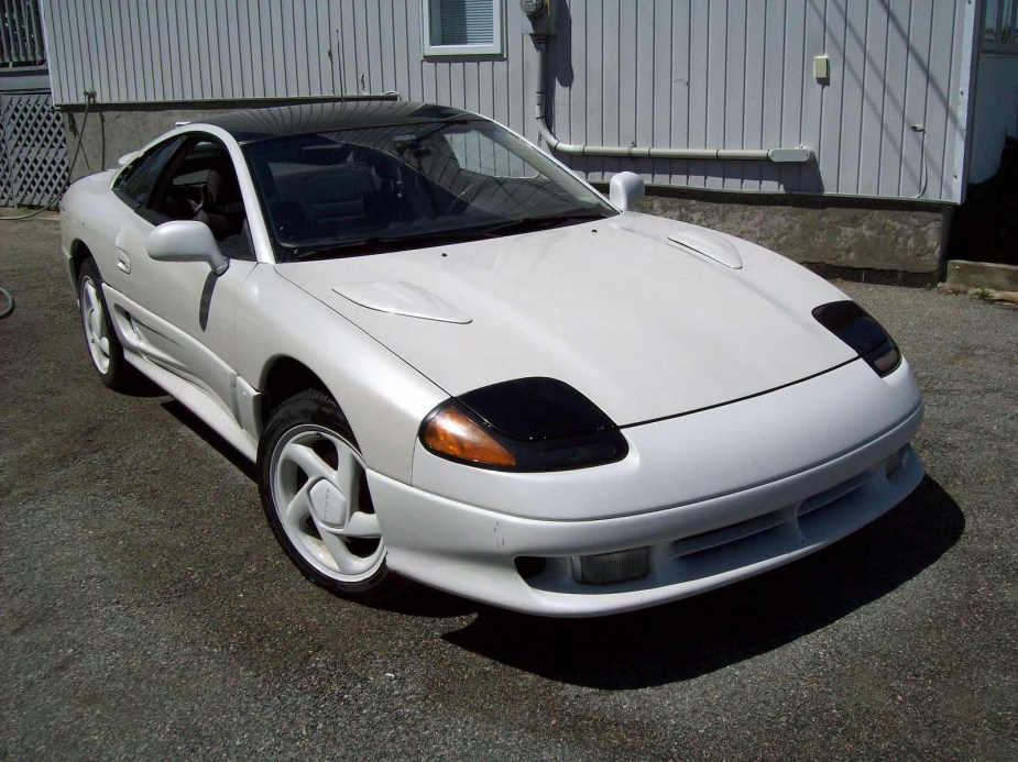 White 1991 Dodge Stealth coupe parked in front of a garage.