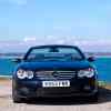 Mercedes-Benz supercar convertible parked in front of a blue ocean with its top down.