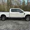 A white Ford F-250 parked on gravel in right profile view