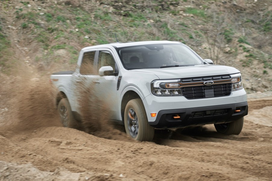 A light grey 2023 Ford Maverick in right front angle view off-roading with dry dirt spraying from right side wheels