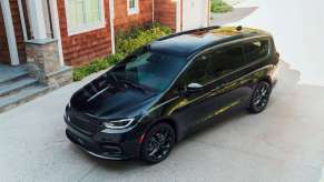 Black Chrysler minivan parked on a sloped driveway.