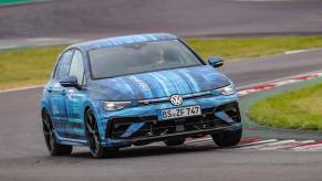 A 2025 Volkswagen Golf R in blue camouflage goes around a track.