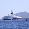 A mega yacht floats off the coast under a cloudless sky.