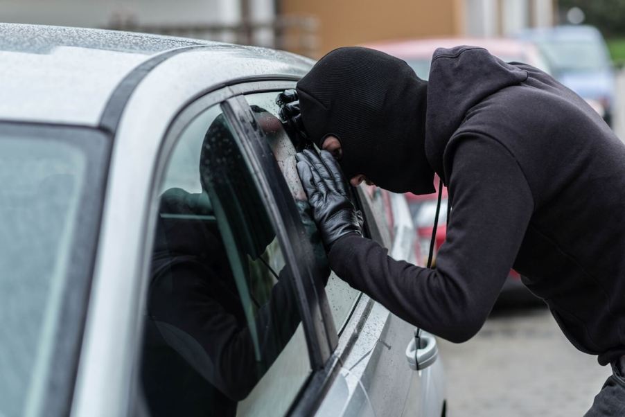 A thief peers through a hatchback's window looking for a gun in the car after noticing a gun decal.