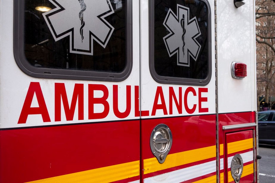 Red and white logo on the back doors of an Ambulance at a crash site