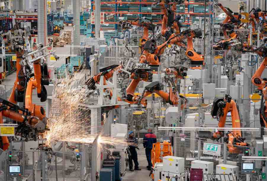 The production line in a BMW factory full of orange robotic arms.