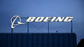 The illuminated Boeing logo on the roof of a dark building at sunset.