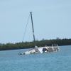 A boat sits in a lagoon after it capsizes.