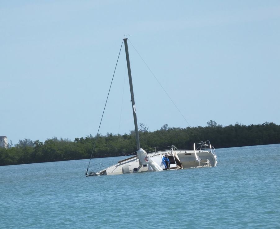 A boat sits in a lagoon after it capsizes.