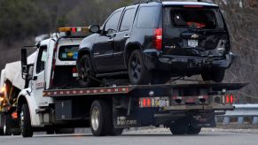 Black Chevy SUV on a tow truck after flipping in crash.