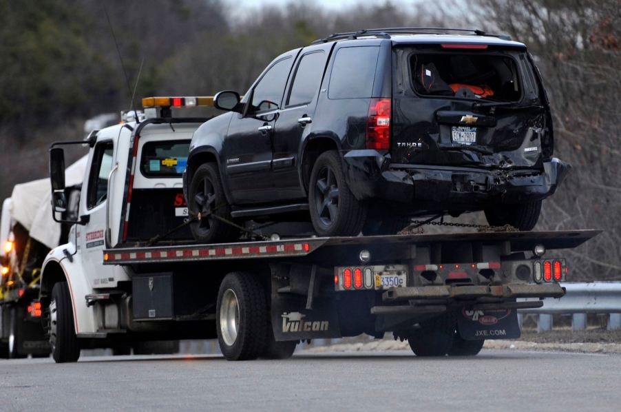 Black Chevy SUV on a tow truck after flipping in crash.