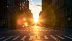 The sun rises over a city street and its standard road lane width.