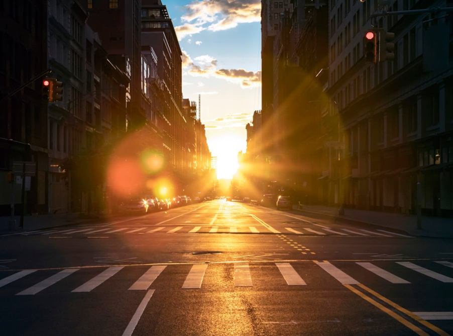 The sun rises over a city street and its standard road lane width.