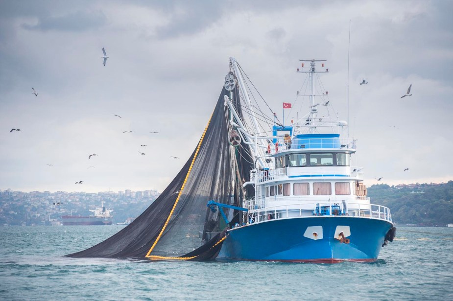 Fishing trawler dragging a net through the open ocean.