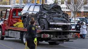 Crashed SUV with a smashed front end sitting on a rollback tow truck