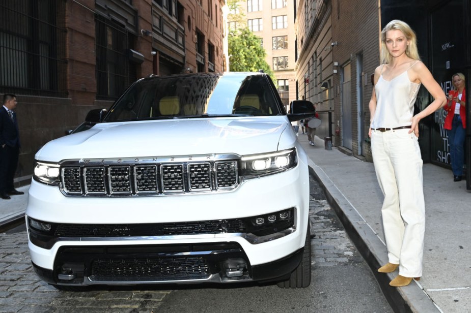 Woman stands next to a white Jeep Wagoneer