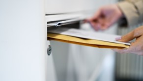 A man slides letters into a mail delivery slot.