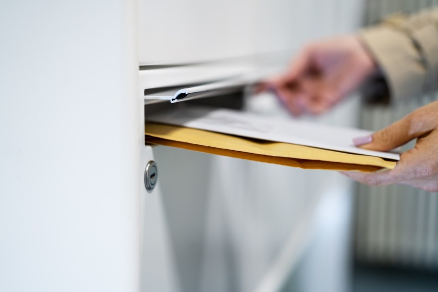 A man slides letters into a mail delivery slot.