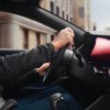 Man holding the steering wheel of a Mazda 3 sports sedan with a red interior