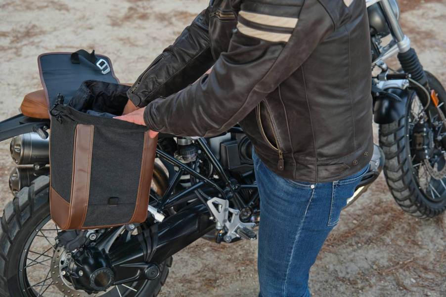 Motorcycle rider reaches into his bike's saddlebag.