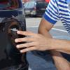 Man points at a dented rear bumper from a crash while parallel parking.