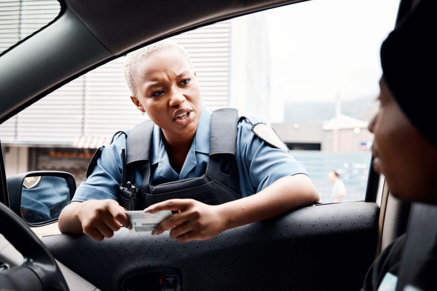 Police officer leans into a window during a traffic stop.