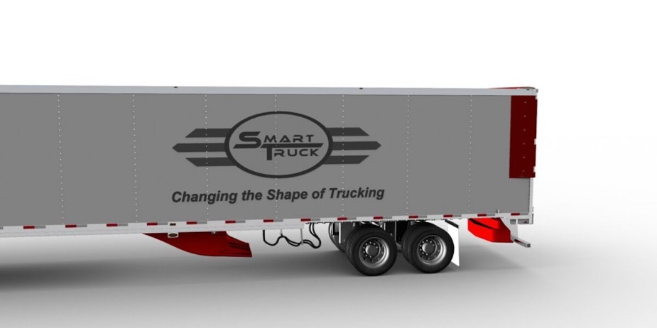 Semi truck trailer with two orange plastic aerodynamic ramps installed underneath.