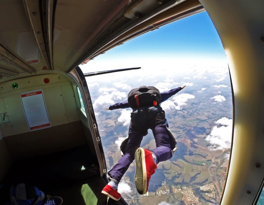 The door of a flying plane with a skydiver jumping out.