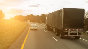 Slow car cruises next to a semi truck in the left lane