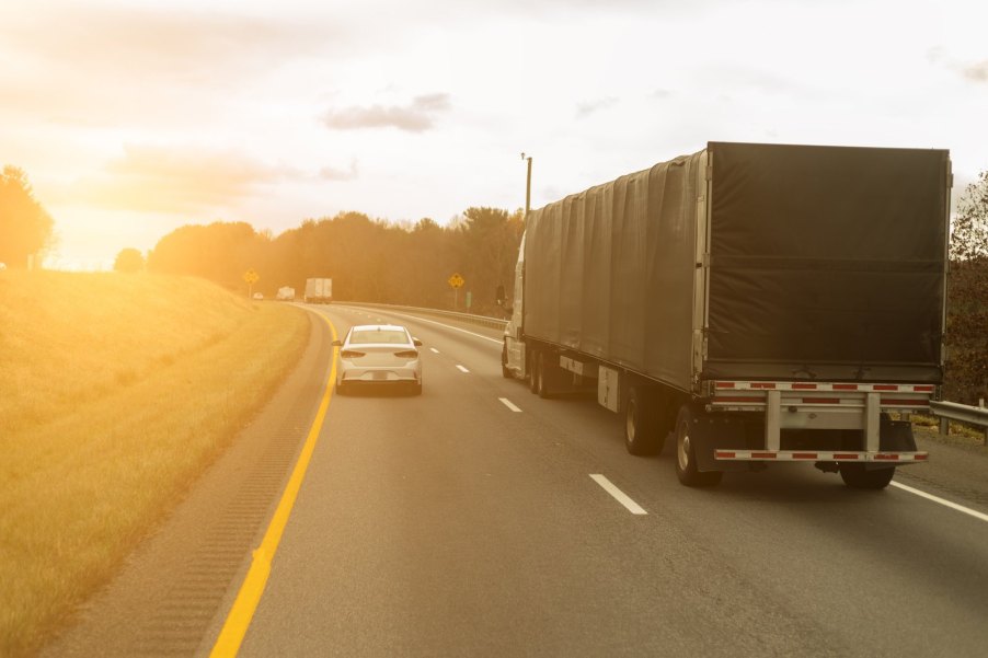 Slow car cruises next to a semi truck in the left lane