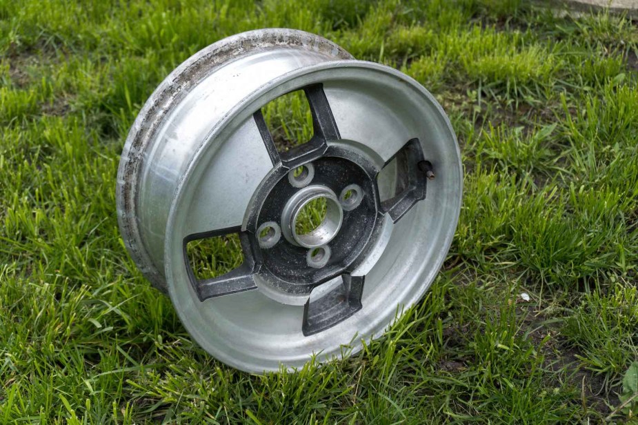 Spare car rim on a grassy field.