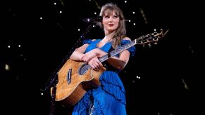 Taylor Swift stands on stage in a blue dress during her Eras tour