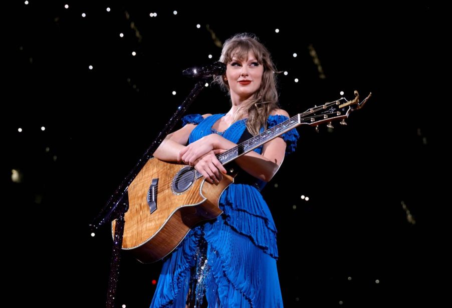 Taylor Swift stands on stage in a blue dress during her Eras tour