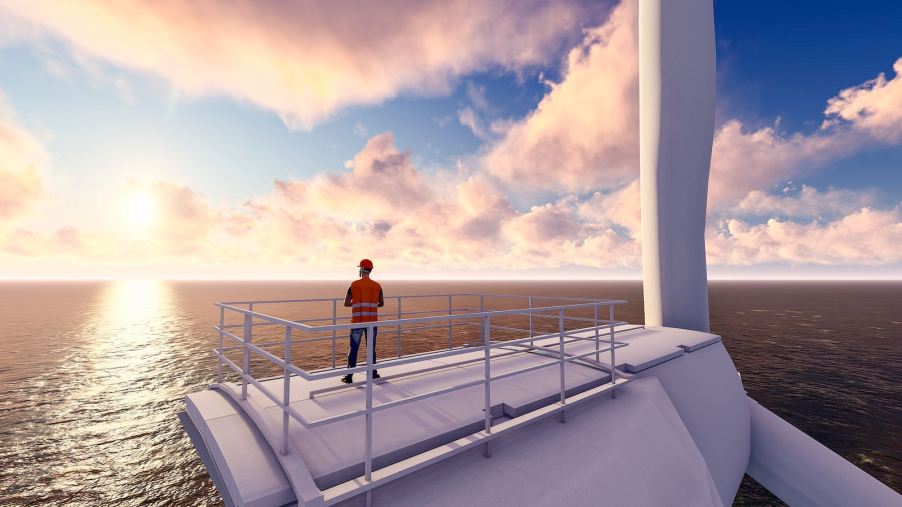 Technician stands on top of a windmill, looking out over the ocean