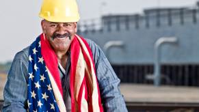 U.S. factory worker with a hard hat and wearing an American flag.