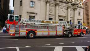 Red fire truck with a tiny cab at the back driving through a Philadelphia parade.