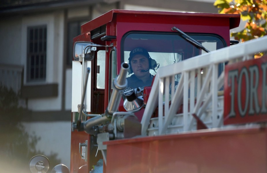 Fireman sitting in the steering cab of a tiller truck ladder truck.