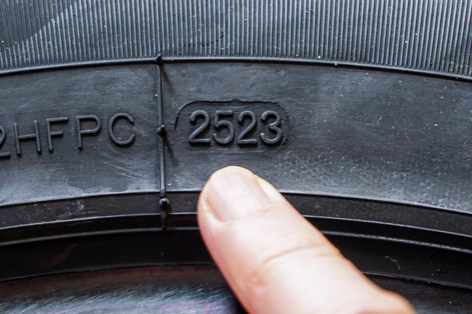 Finger pointing at the date code of tires from 2023