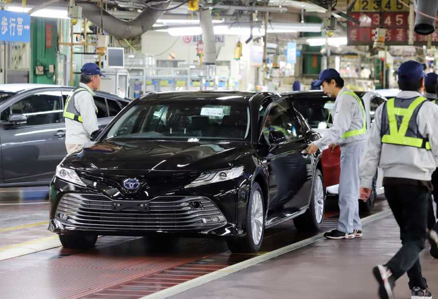 Japanese factory workers finish the assembly of a Toyota Camry