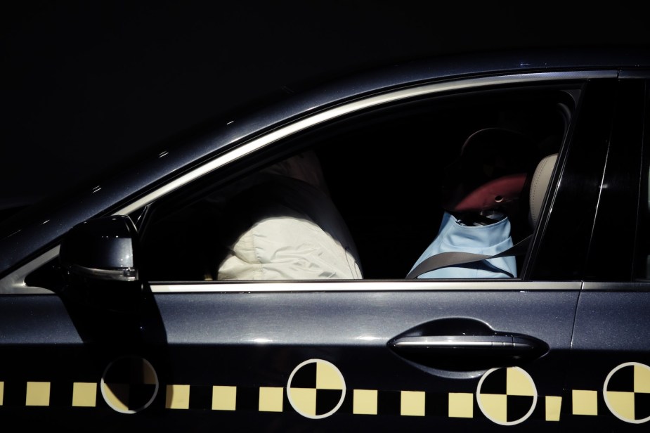 Crash test dummy and deployed airbag during safety test.