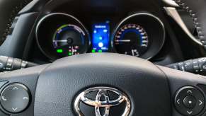 The Toyota logo on the steering wheel of a compact car.