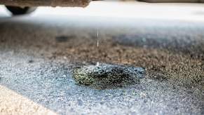 Water dripping from beneath a car and gathering in a puddle.