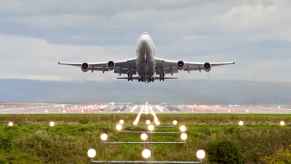 A commercial plane taking off in direct front view with runway in mid background