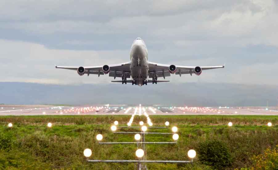 A commercial plane taking off in direct front view with runway in mid background