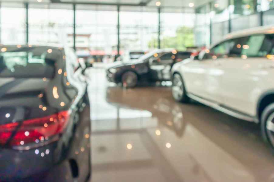 A blurred image of the showroom floor at a car dealership with shiny floor and several new cars