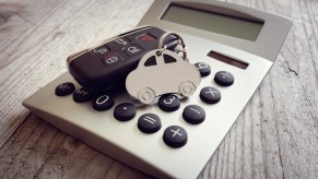 A representation of a car payment using a handheld calculator on a table with a car keychain on top