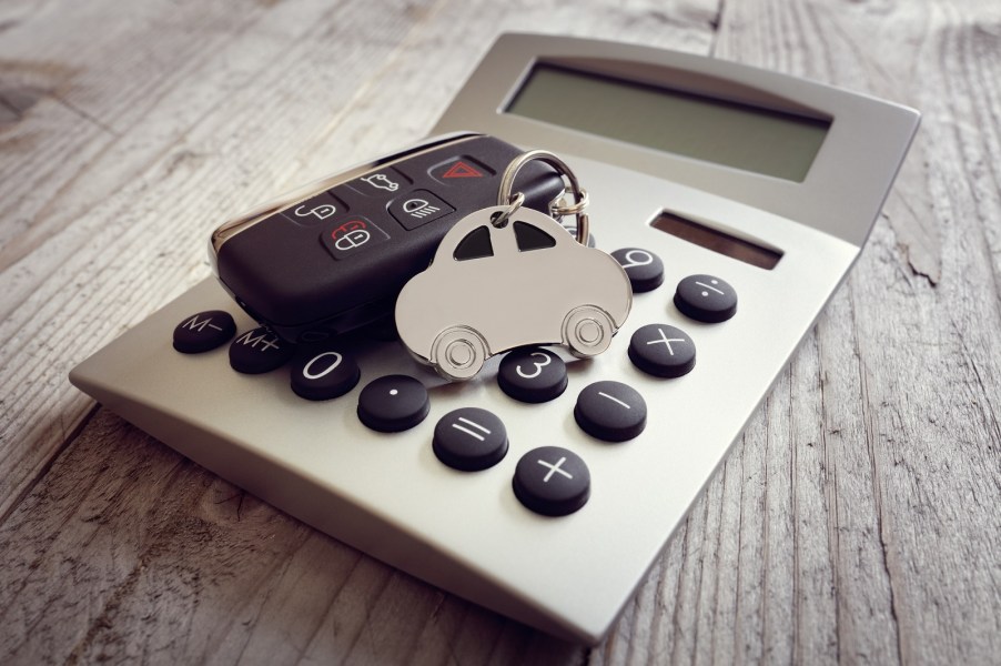 A representation of a car payment using a handheld calculator on a table with a car keychain on top