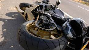 A motorcycle rider takes a picture of their bike after a crash on a two-lane highway.