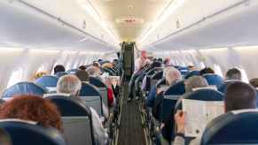 A view of airplane passengers sitting in their seats from behind rear of plane